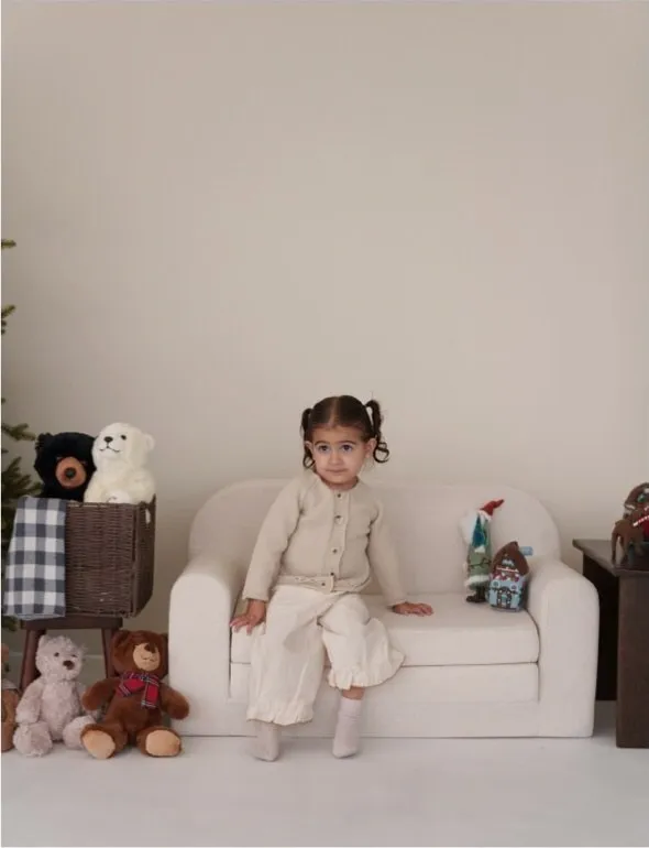 Niña sentada en el sillón con peluches